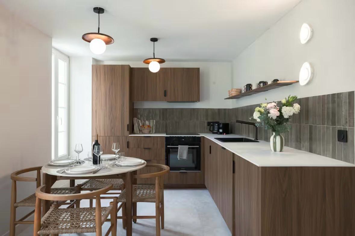La cuisine équipée en bois et sa table ronde conviviale, baignée de lumière naturelle.