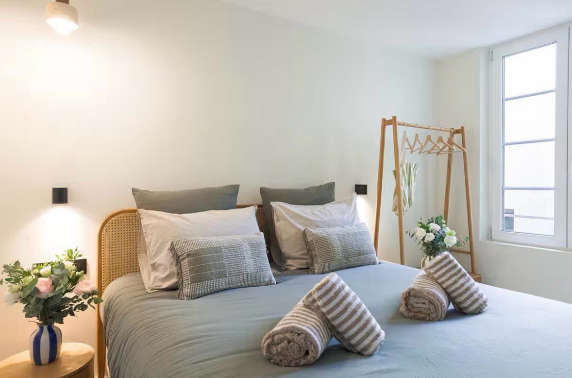 Seconde chambre apaisante aux tons vert d'eau, tête de lit en cannage et linge soigné.