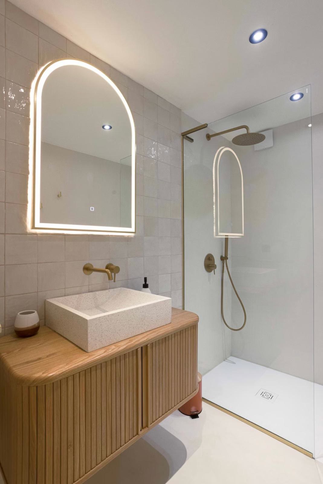 Salle de bain moderne, vasque en terrazzo, robinetterie dorée et douche à l'italienne.