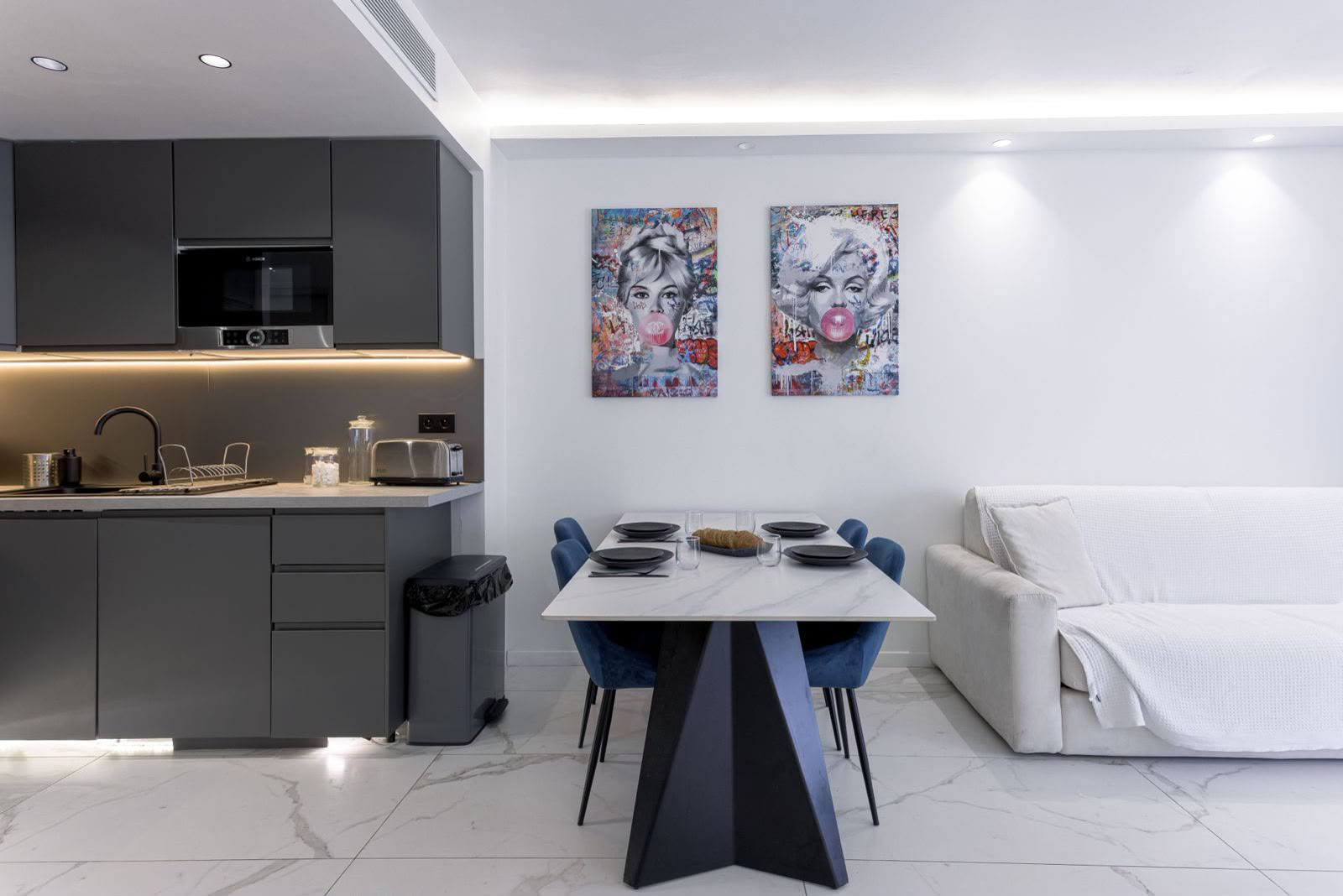 Le coin repas et la cuisine équipée anthracite, sous les toiles pop-art de Bardot et Marilyn.